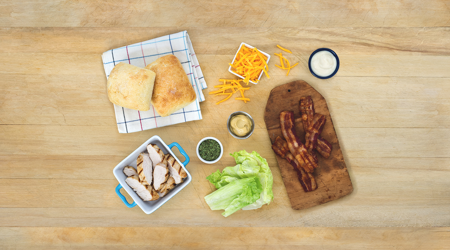 Ingredients for Dijon Cheddar Chicken Melt on a wooden countertop