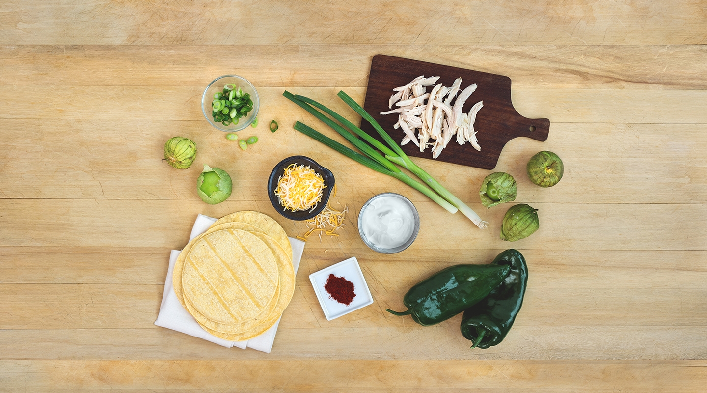 Ingredients for Roasted Tomatillo & Chicken Enchilada Casserole on a wooden countertop