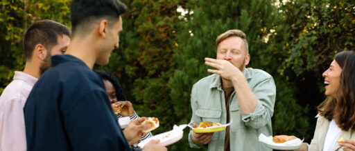 A group of people standing laughing at a backyard bbq.