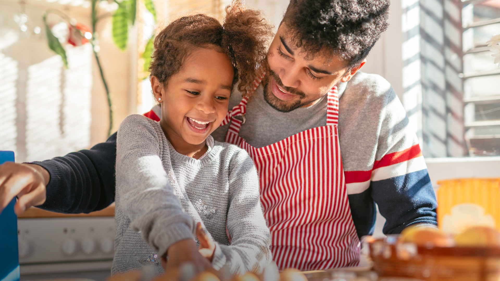 A father and daughter cook together in the kitchen