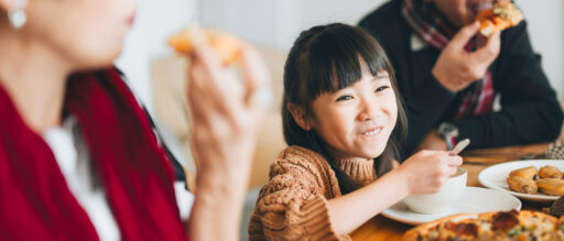 A young girl eats a dinner with her family