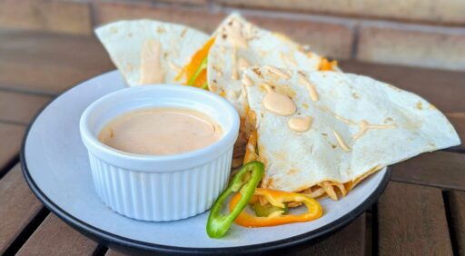 Quesadillas on a plat with veggie garnish and buffalo ranch dip